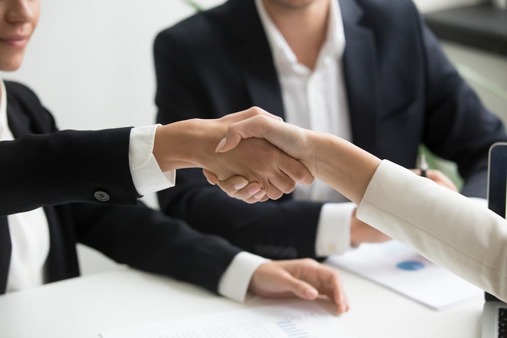 Two professionals shaking hands across a meeting table